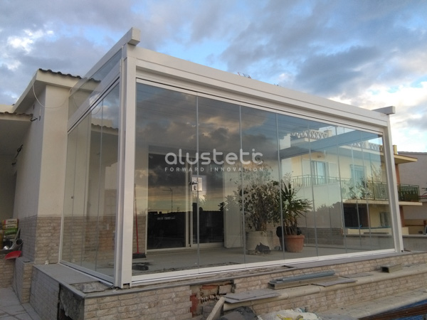 Pérgola tensada con cortinas de cristal en una terraza exterior