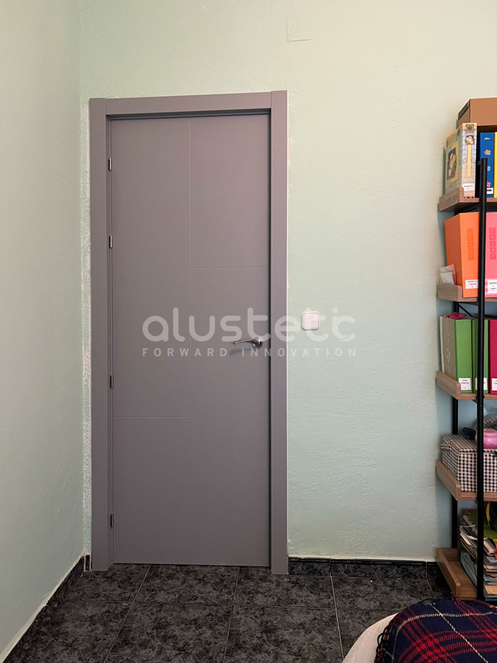 Porta interior d'alumini gris instal·lada en una habitació